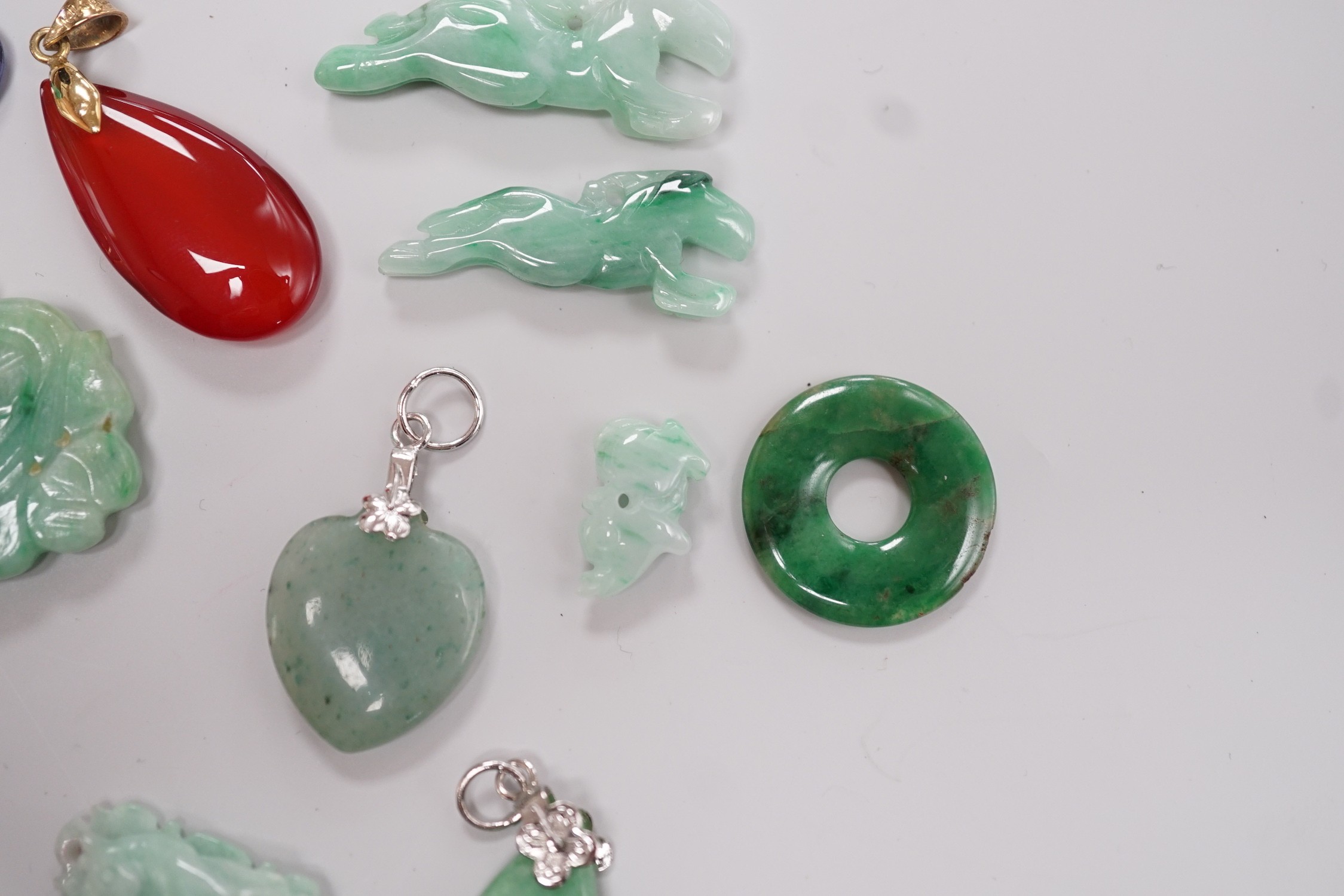 Twelve assorted carved jadeite items including five pendants, largest 40mm, a 14k mounted carnelian pendant and an unmounted pear cut simulated Tanzanite.